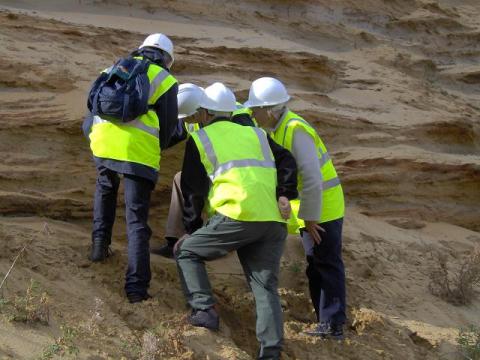 A group intently checking out a fossil from a quarry visit